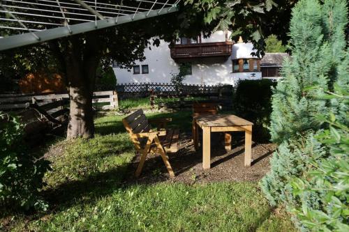 a wooden chair and a table in a yard at Bikers Paradise Apartment in Oberlängenfeld