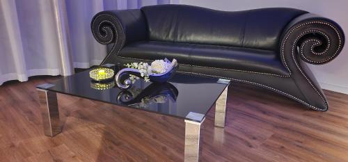 a black leather couch and a glass coffee table at Privat-Spa mit Whirlpool und Sauna in Sursee in Sursee