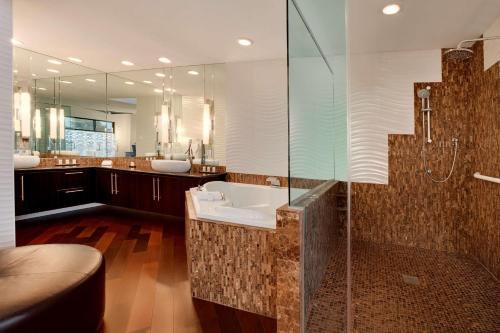 a bathroom with a sink and a glass shower at Embassy Suites by Hilton Scottsdale Resort in Scottsdale