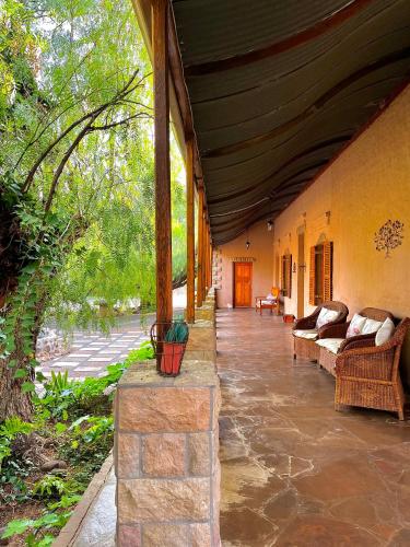 a porch of a house with couches and trees at The Vale Karoo Farm in Nelspoort