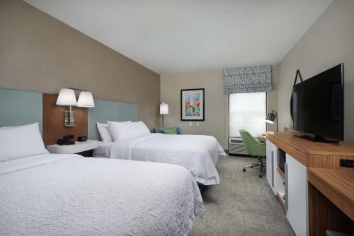 a hotel room with two beds and a flat screen tv at Hampton Inn Louisville/I-65/Brooks Road in Brooks