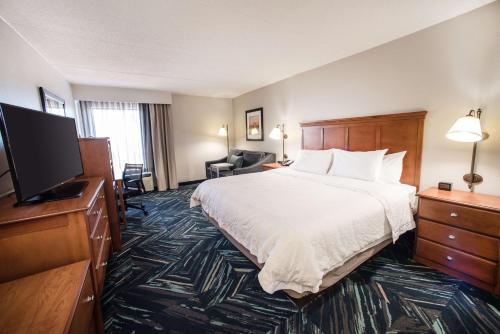 a hotel room with a bed and a flat screen tv at Hampton Inn Clarksville in Clarksville