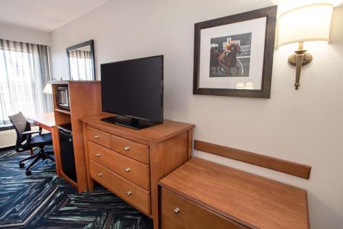 a hotel room with a television on a dresser with a desk at Hampton Inn Clarksville in Clarksville