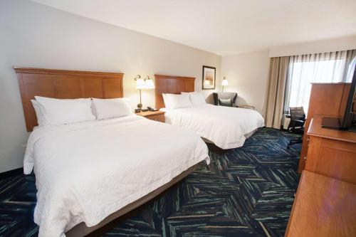a hotel room with two beds and a television at Hampton Inn Clarksville in Clarksville