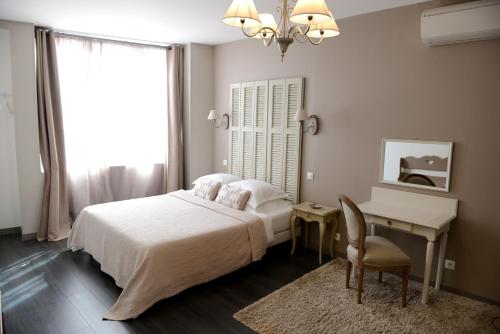 a bedroom with a bed and a table and a desk at La Maison d'Hotes de Saint Leger in Saint-Léger-en-Yvelines
