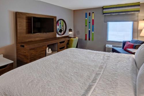 a bedroom with a bed and a tv and a couch at Hampton Inn New Albany Louisville West in New Albany