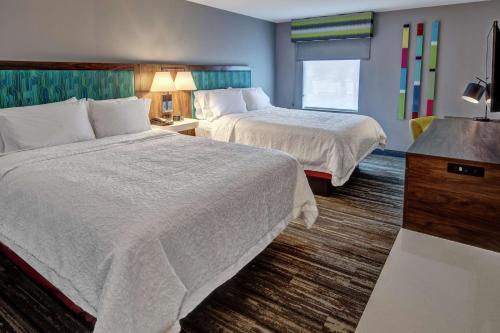 a hotel room with two beds and a television at Hampton Inn New Albany Louisville West in New Albany