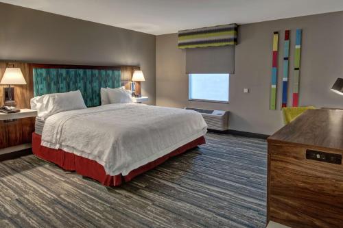a hotel room with a bed and a large window at Hampton Inn New Albany Louisville West in New Albany