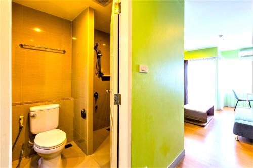 a bathroom with a toilet and a room with a bed at Nest n Rest Hotel in Ban Bang Toei (1)