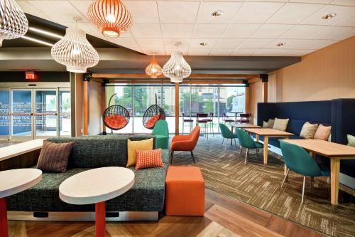 a restaurant with a couch and tables and chairs at Tru By Hilton Louisville Airport in Louisville