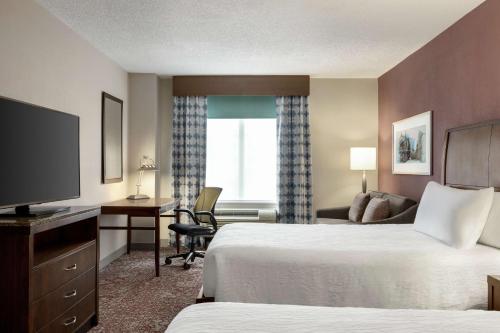 Habitación de hotel con 2 camas, escritorio y TV. en Hilton Garden Inn Louisville Downtown, en Louisville