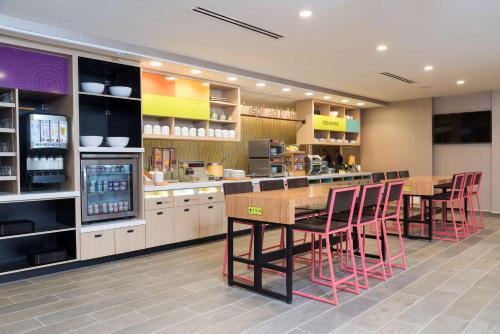 a restaurant with a bar with red chairs and a counter at Home2 Suites by Hilton Louisville Downtown NuLu in Louisville