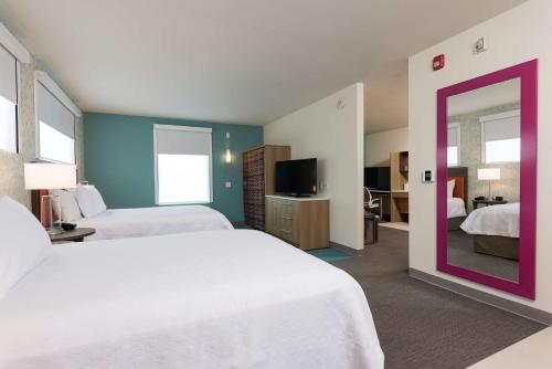 a hotel room with two beds and a mirror at Home2 Suites by Hilton Louisville Downtown NuLu in Louisville