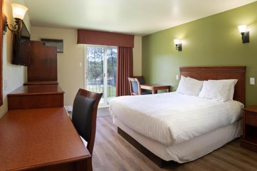 a hotel room with a bed and a desk and a table at Hôtel Marineau Mattawin in Trois Rives