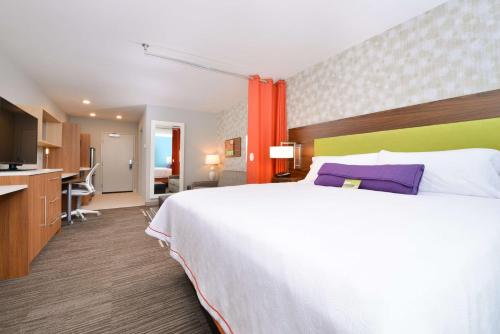 a hotel room with a large bed and a kitchen at Home2 Suites By Hilton DuPont in DuPont