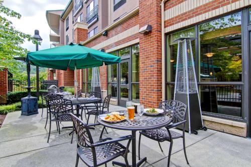 a patio with tables and chairs and an umbrella at Hilton Garden Inn Seattle/Issaquah in Issaquah