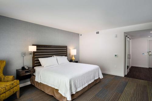 a bedroom with a large white bed and a yellow couch at Hampton Inn & Suites by Hilton Seattle/Northgate in Seattle