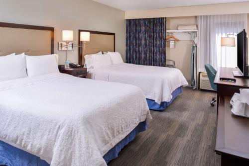 a hotel room with two beds and a flat screen tv at Hampton Inn Seattle Airport in SeaTac