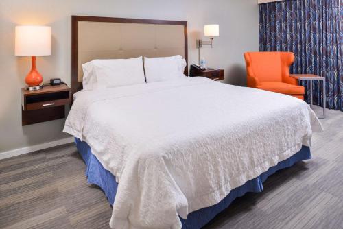 a bedroom with a large bed and an orange chair at Hampton Inn Seattle Airport in SeaTac