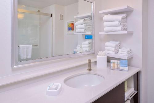 uma casa de banho com lavatório, espelho e toalhas em Hampton Inn Seattle Airport em SeaTac