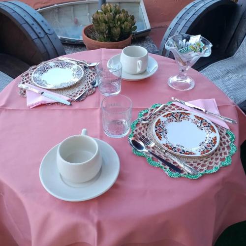 a pink table with plates and cups on a pink table cloth at B&b Ammentos in Magomadas