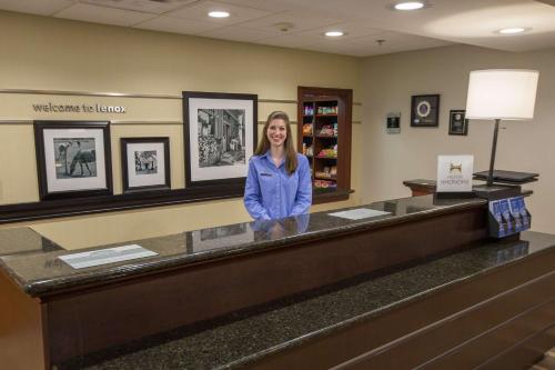 a woman standing at a counter in a waiting room at Hampton Inn & Suites Berkshires-Lenox in Lenox