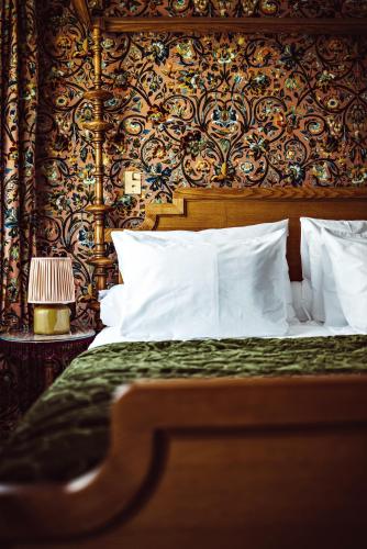 a bed with white pillows and a patterned wall at Hôtel Eldorado Paris in Paris