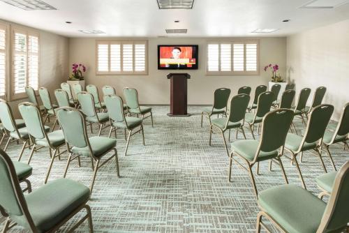 a conference room with chairs and a podium with a screen at DoubleTree by Hilton Campbell - Pruneyard Plaza in Campbell