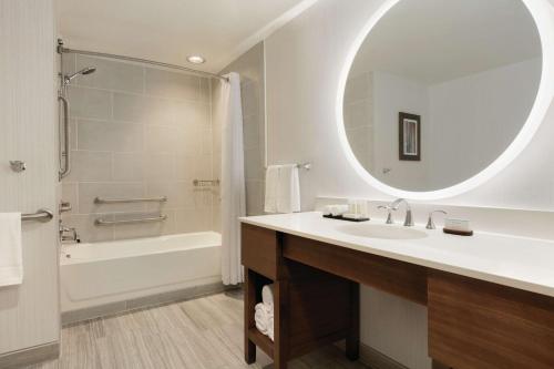 a bathroom with a sink and a tub and a mirror at Embassy Suites By Hilton South Jordan Salt Lake City in South Jordan