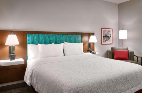 um quarto com uma cama grande e uma cadeira vermelha em Hampton Inn Draper Salt Lake City, Ut em Draper