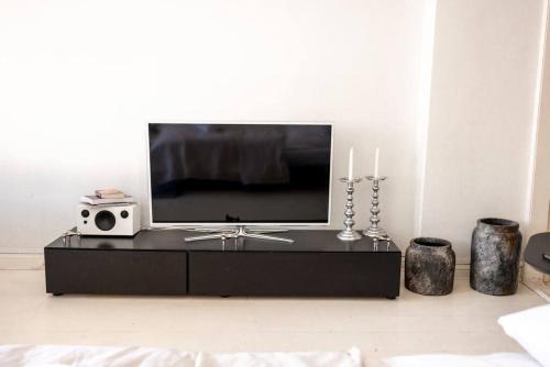 a living room with a tv on a black entertainment center at 2ndhomes Stylish Studio in Helsinki Design District in Helsinki