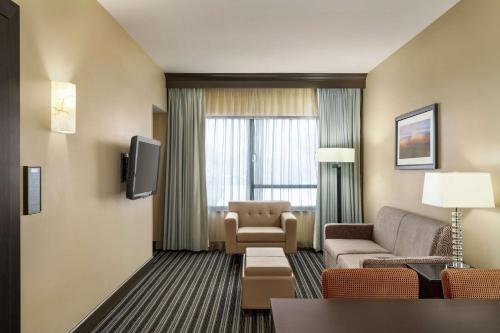 a hotel room with a couch and a chair and a tv at Embassy Suites by Hilton Salt Lake West Valley City in West Valley City