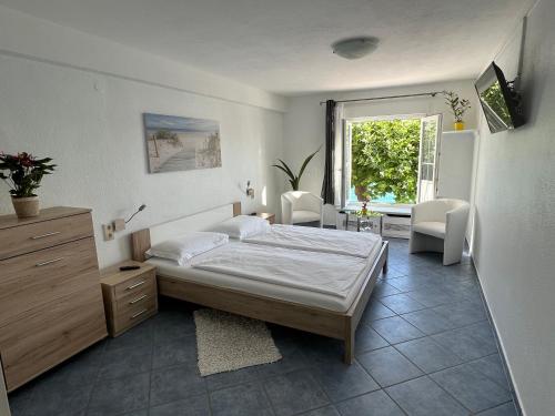 a bedroom with a bed and a desk and a window at Hotel la Perla in Meersburg