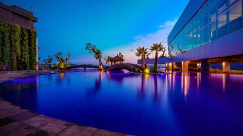 - une grande piscine en face d'un bâtiment la nuit dans l'établissement FUGO Hotel Samarinda, à Samarinda