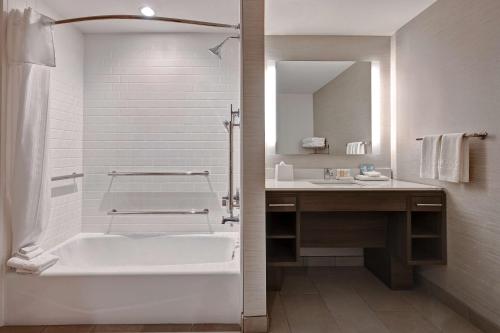 a white bathroom with a tub and a sink at Home2 Suites By Hilton Anaheim Resort in Anaheim