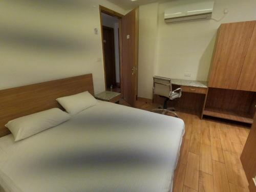 a bedroom with a white bed and a desk at OLIVIA HOME STAY in Dehradun