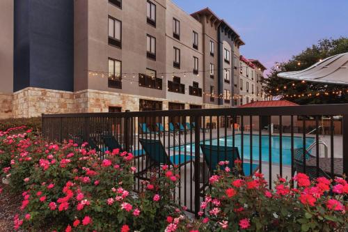 a hotel with a pool and some pink flowers at Hampton Inn & Suites San Marcos in San Marcos