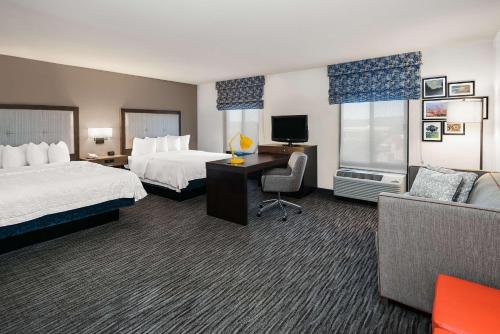 a hotel room with two beds and a desk and a couch at Hampton Inn & Suites San Marcos in San Marcos