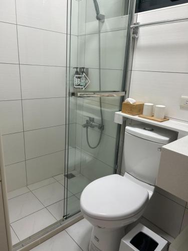 a bathroom with a toilet and a glass shower at Shigang Homestay市港行旅 in Jinhu