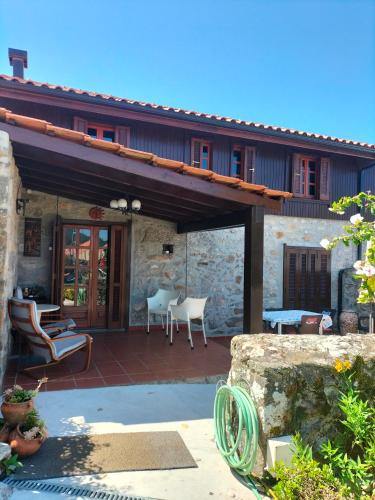 a stone house with a patio with chairs and tables at CASA DE MADEIRA E PEDRA in Afife