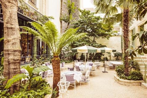 d'une terrasse avec des tables, des chaises et des palmiers. dans l'établissement Hôtel Eldorado Paris, à Paris