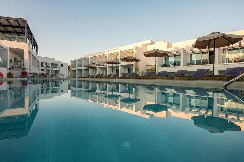 a swimming pool with chairs and umbrellas next to a building at Mirage Bleu Hotel in Tragaki