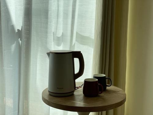 a coffee maker and two mugs on a table next to a window at Shigang Homestay市港行旅 in Jinhu