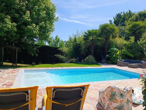 - deux chaises et une piscine dans la cour dans l'établissement Spacieux et Lumineux appartement dans Villa Contemporaine avec Piscine chauffée privative près Golf d'Arcangues, à Bidart