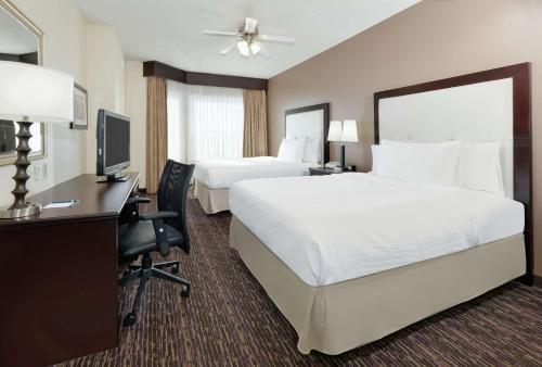 ウィチタフォールズにあるHomewood Suites Wichita Fallsのベッド2台、デスク、テレビが備わるホテルルームです。