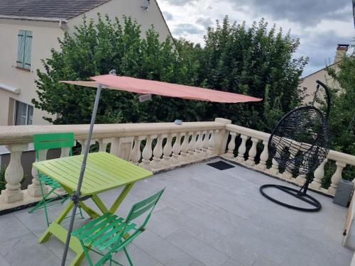 a pink umbrella and a table and chairs on a balcony at Persan Studio avec Terrasse in Persan