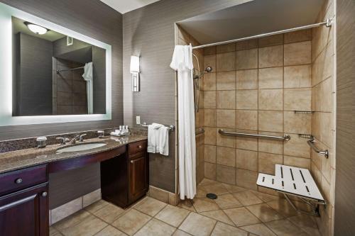 a bathroom with a shower and a sink and a mirror at Homewood Suites Wichita Falls in Wichita Falls