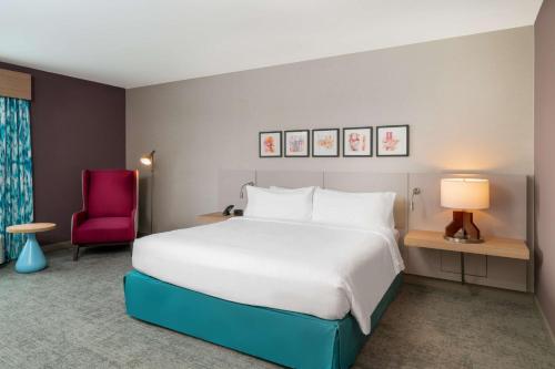 a bedroom with a large bed and a red chair at Hilton Garden Inn Brunswick in Brunswick