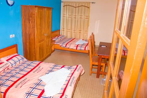 1 dormitorio con 2 camas, mesa y escritorio en Abomey Events, en Abomey