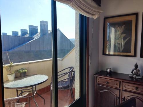 a room with a balcony with a table and a window at Los Abriles in Baiona